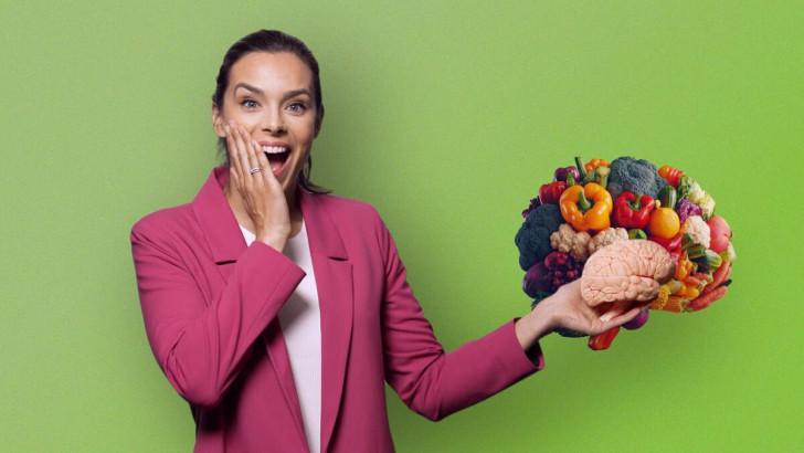 Marine Lorphelin tient dans sa main gauche un cerveau, devant un autre constitué de plusieurs légumes